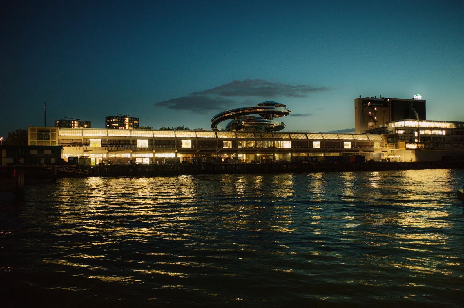 Het verlichte museumgebouw aan het water in de schemering.