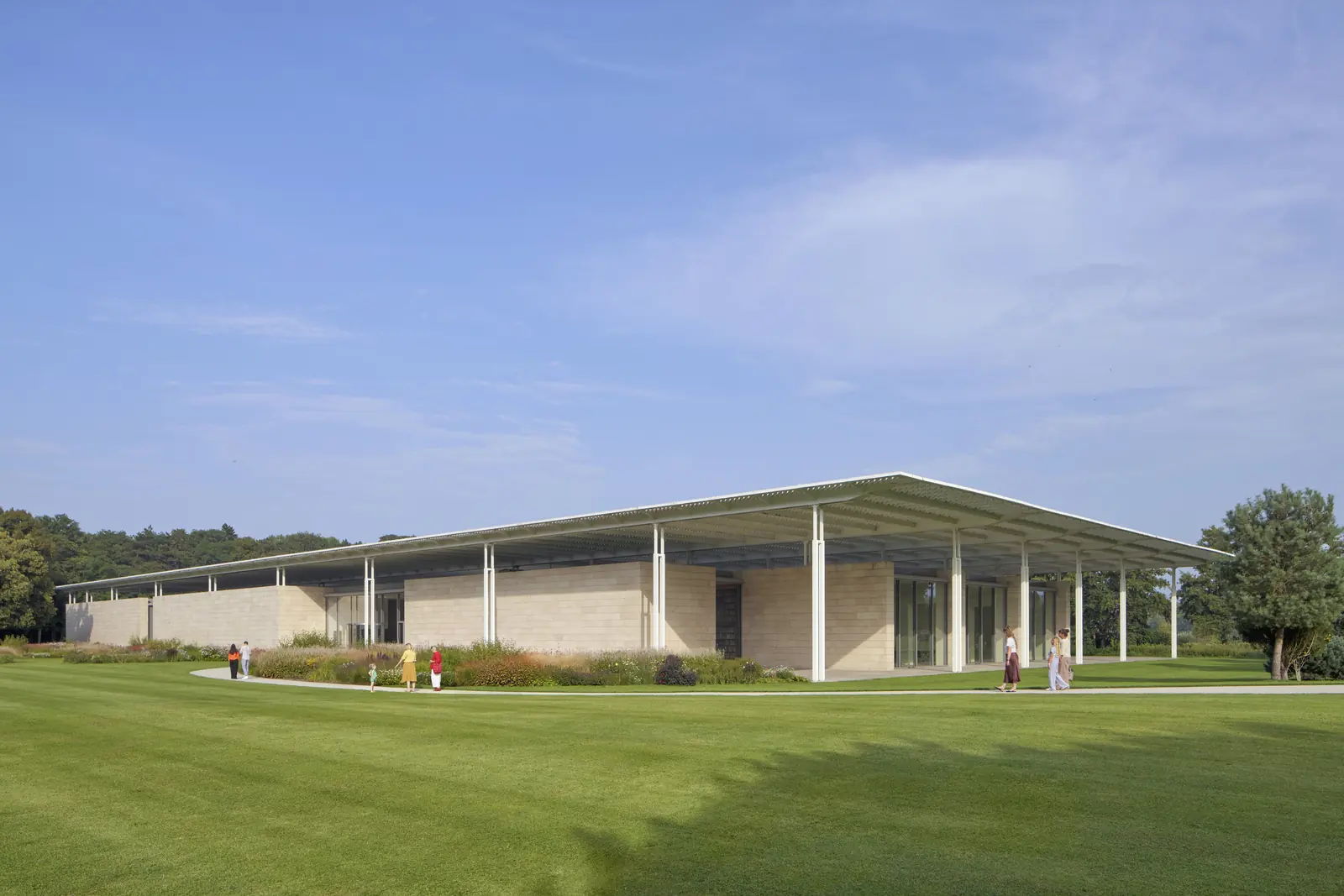 Het lange, lage museumgebouw met een overstekend dak, gezien over een groot grasveld.