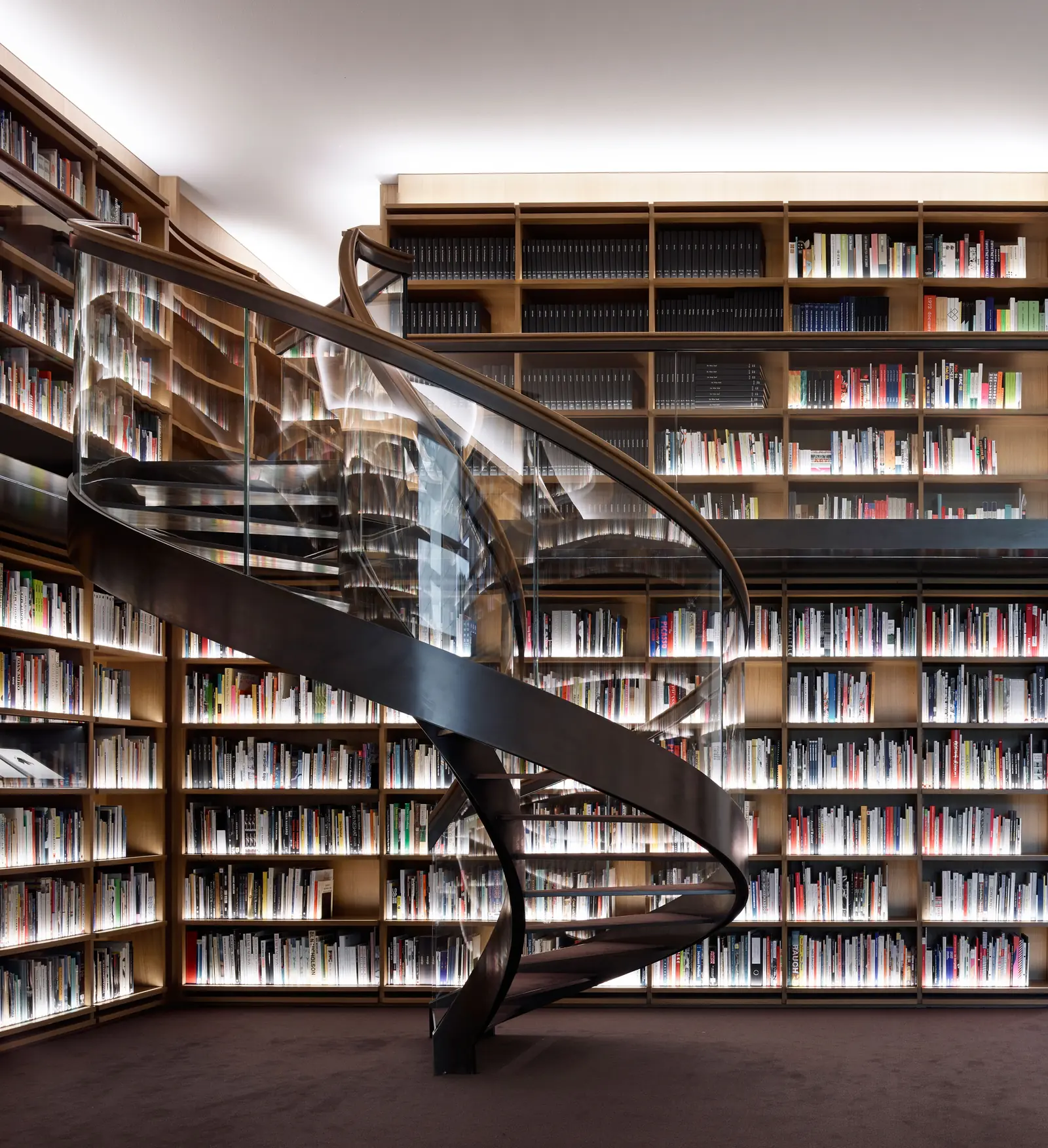 Een wenteltrap tussen hoge boekenkasten vol boeken.