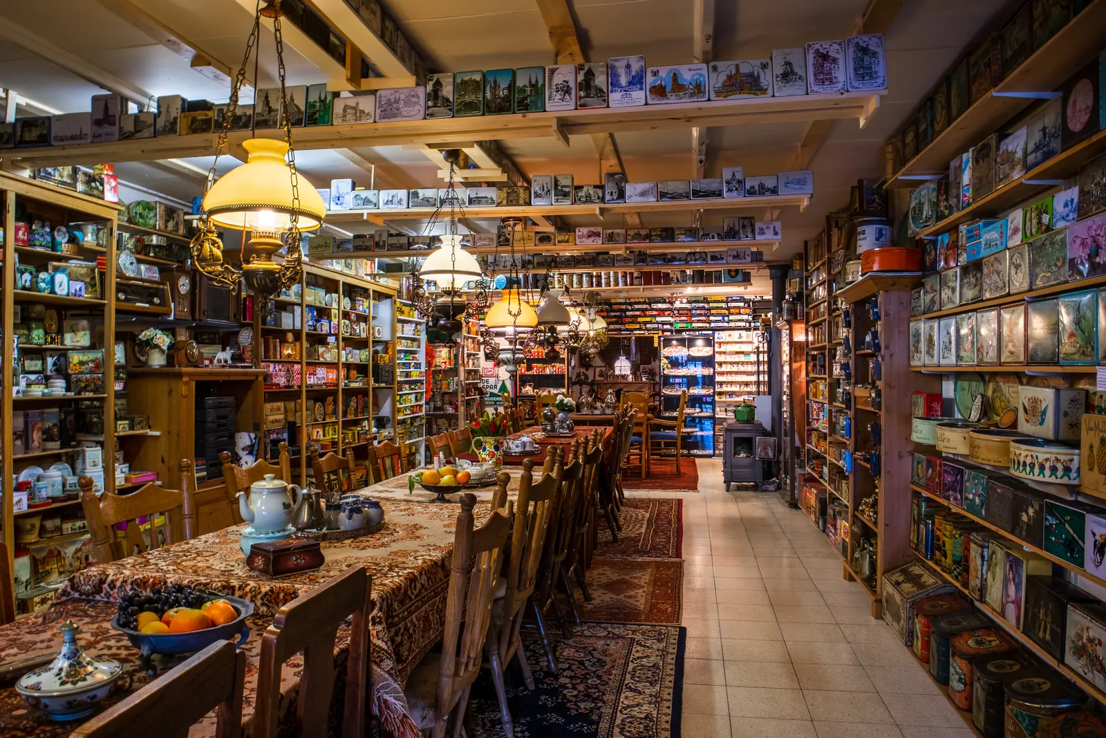 Une longue salle de musée remplie d’étagères de boîtes en fer-blanc, avec une table au centre.