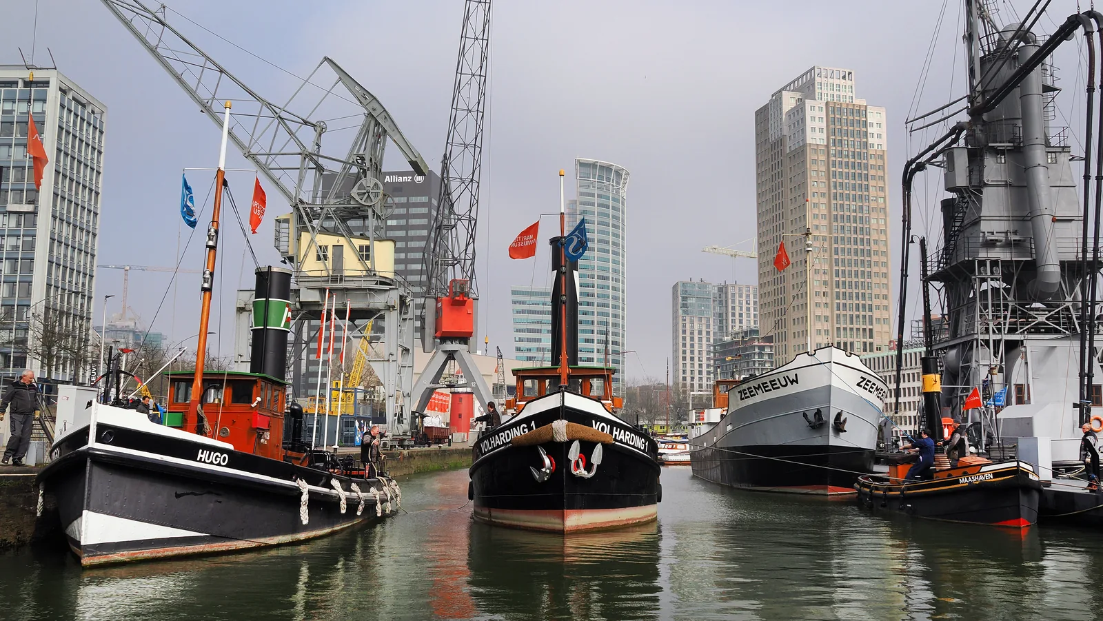 Historische schepen en havenkranen aan de kade van de museumhaven in Rotterdam.