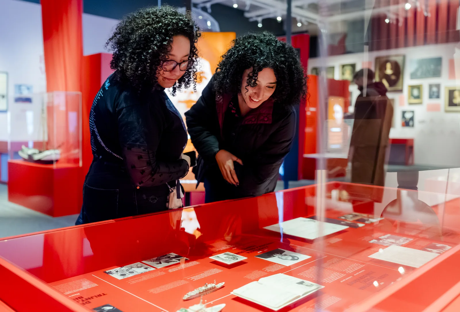 Twee bezoekers bekijken documenten achter glas in Maritieme Vrouwen.