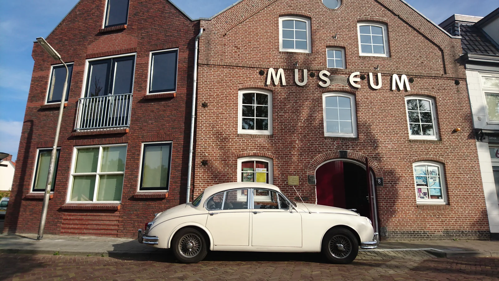 Gevel van ’t Andere Museum met een witte Jaguar voor de deur.