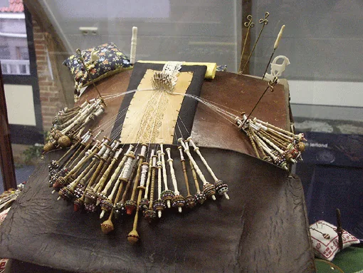 Kantkloskussen uit Tønder, Denemarken, in een vitrine.
