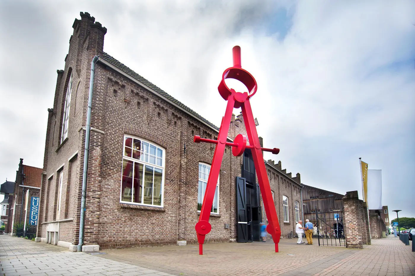 Gevel van het Cuypershuis met een groot rood passerbeeld ervoor.