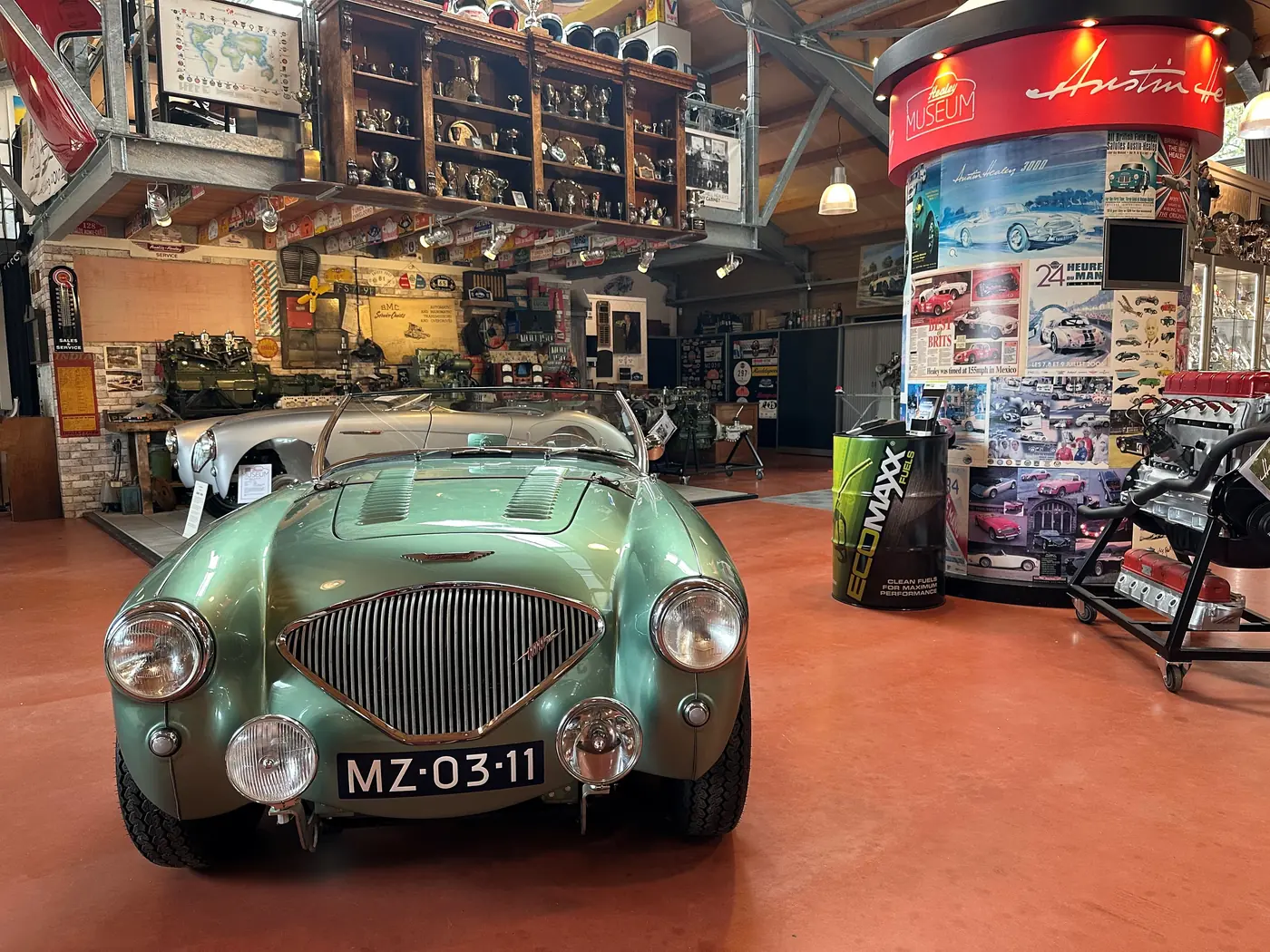 Groene klassieke sportauto tussen museumvitrines.