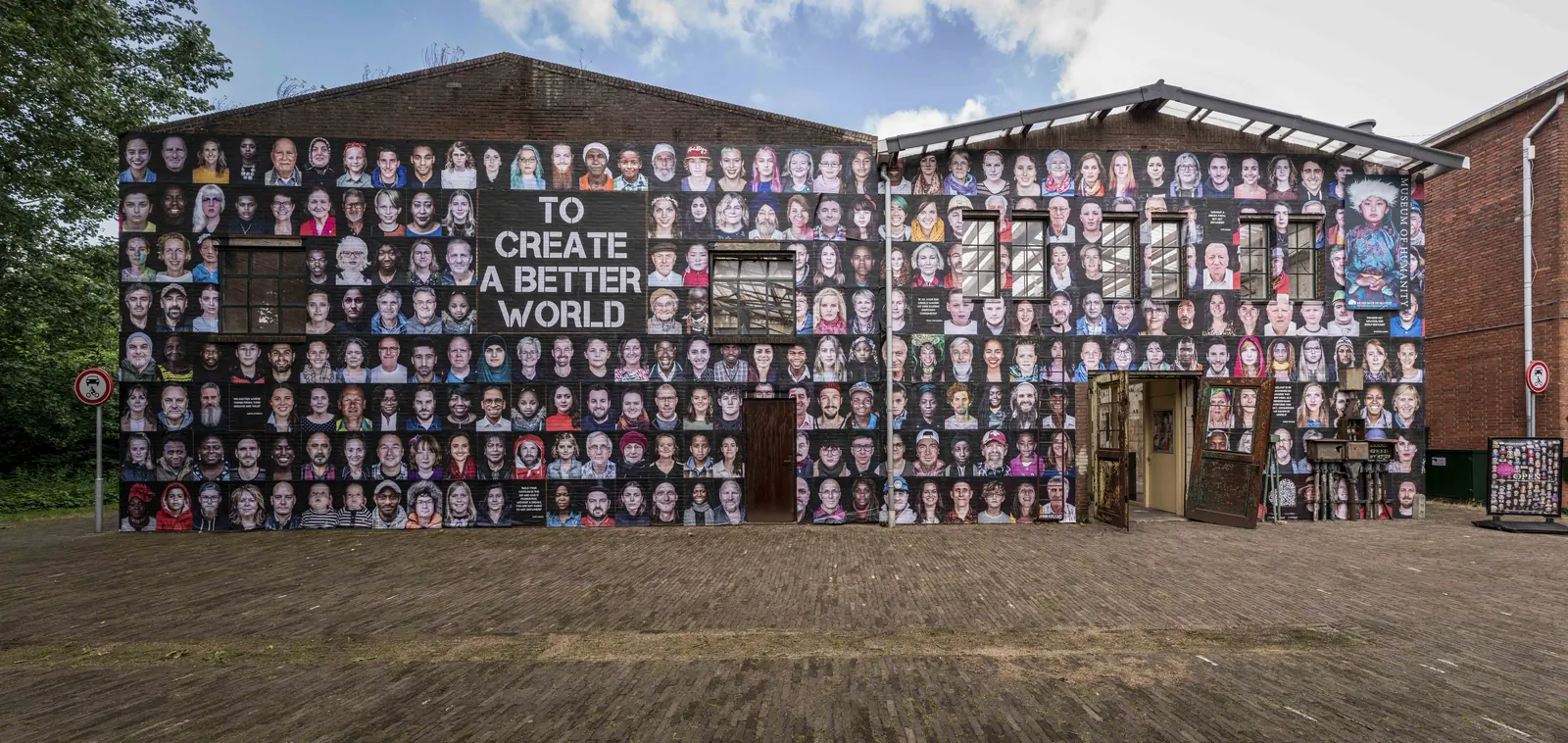 Buitenzijde van Museum of Humanity met een wand vol portretten.