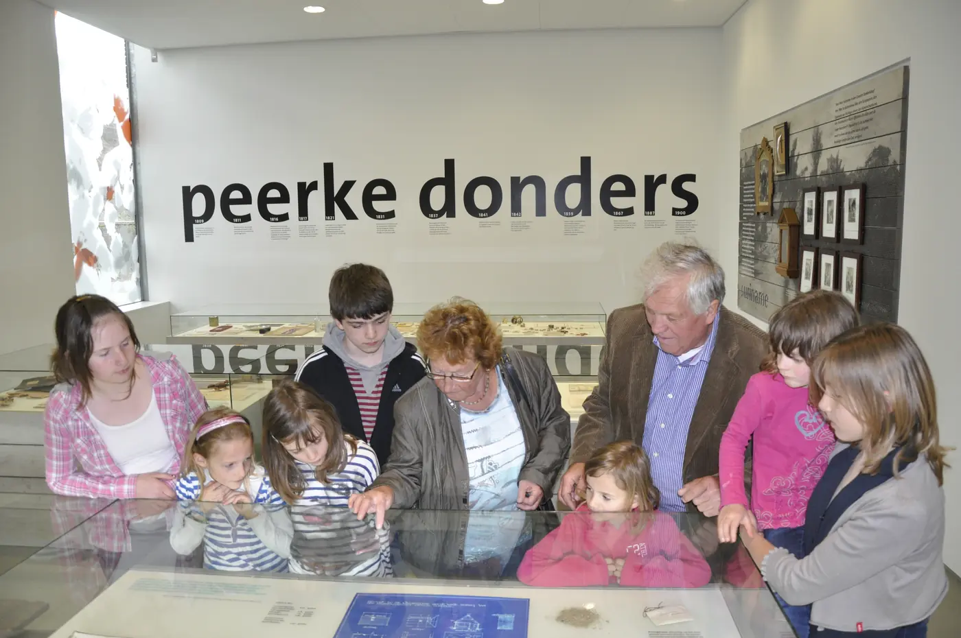 Adultes et enfants observant ensemble des objets pendant une visite guidée.