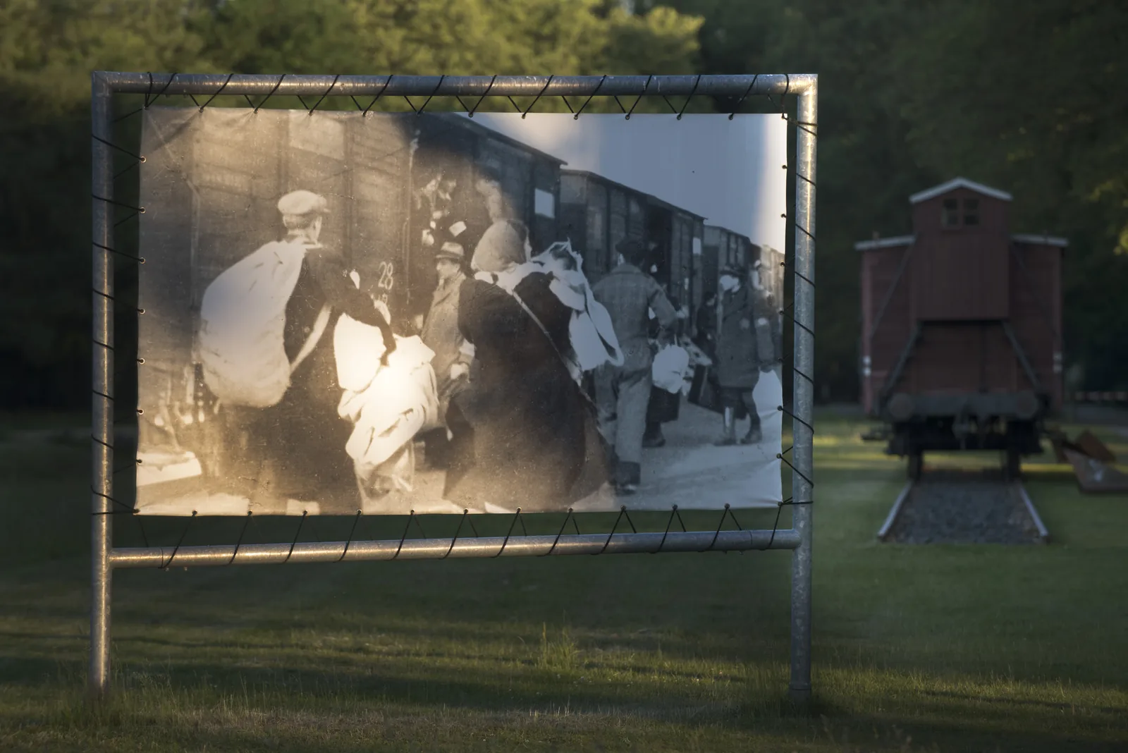 Outdoor historical photo panel beside a railway wagon at the former camp.
