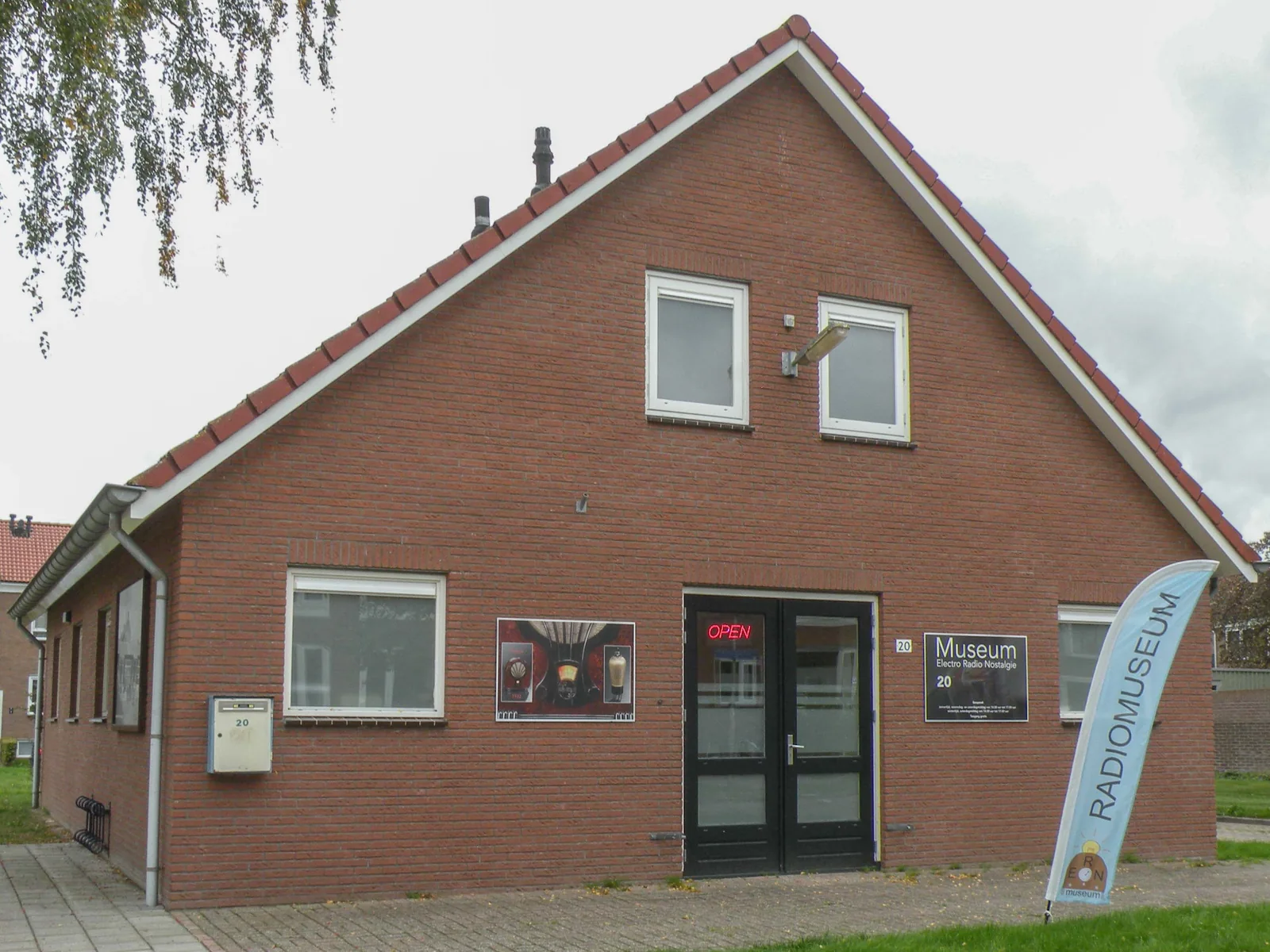 Brick front of the museum with its sign and a flag by the entrance.