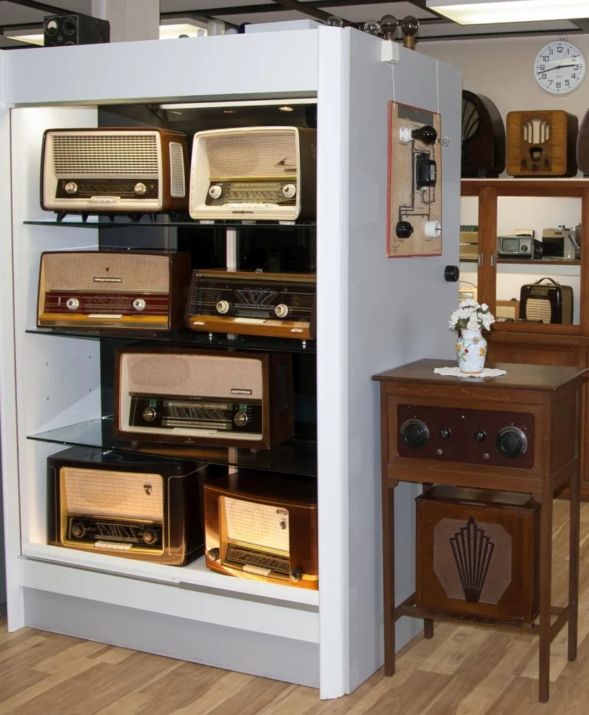 Display case with several radio sets and a wooden set on a table.
