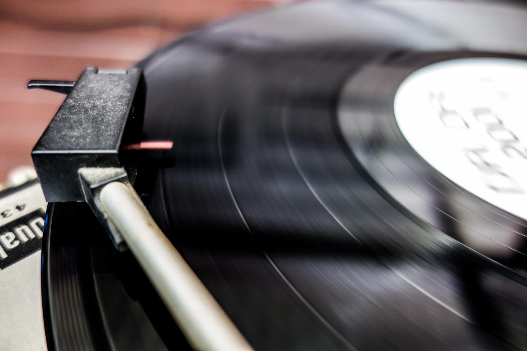 Aiguille et bras de lecture au-dessus des sillons d’un disque vinyle noir.