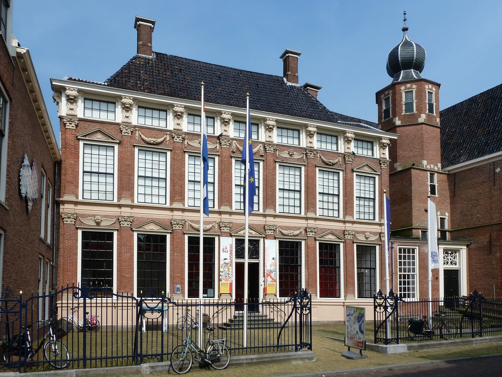 Ornate brick façade of the Princessehof, with tall windows, flags and a fence.
