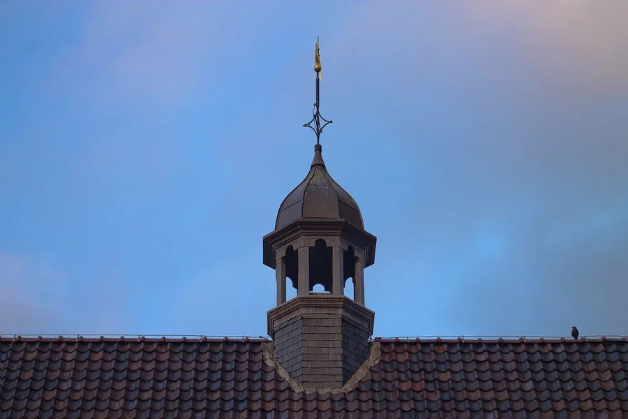 Roof and small tower of Rijksmuseum Twenthe against the evening sky.