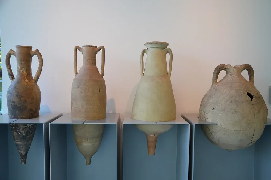 Four Roman amphorae on plinths in a former museum display.