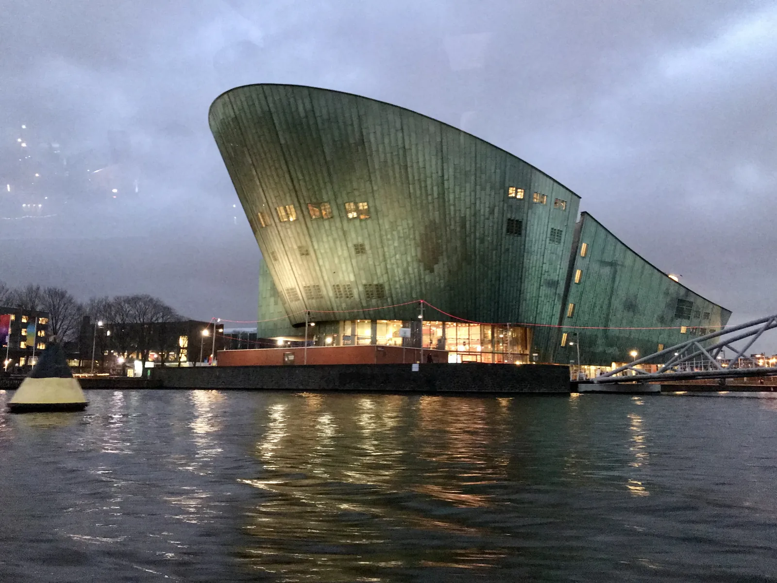 NEMO met verlichte ramen en weerspiegeling in het Oosterdok.