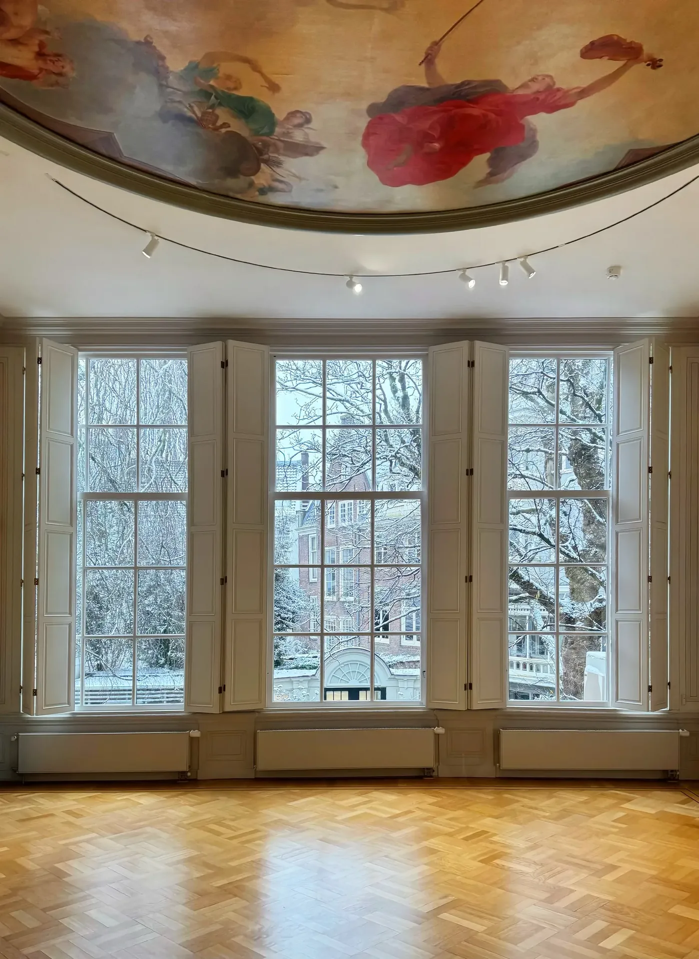 Room with a painted ceiling and tall windows overlooking the garden.