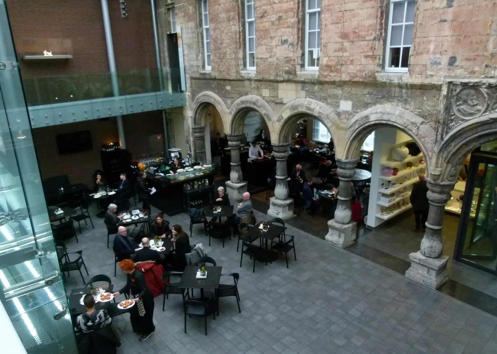 Colonnade en pierre près de la cour du musée, avec une passerelle moderne.