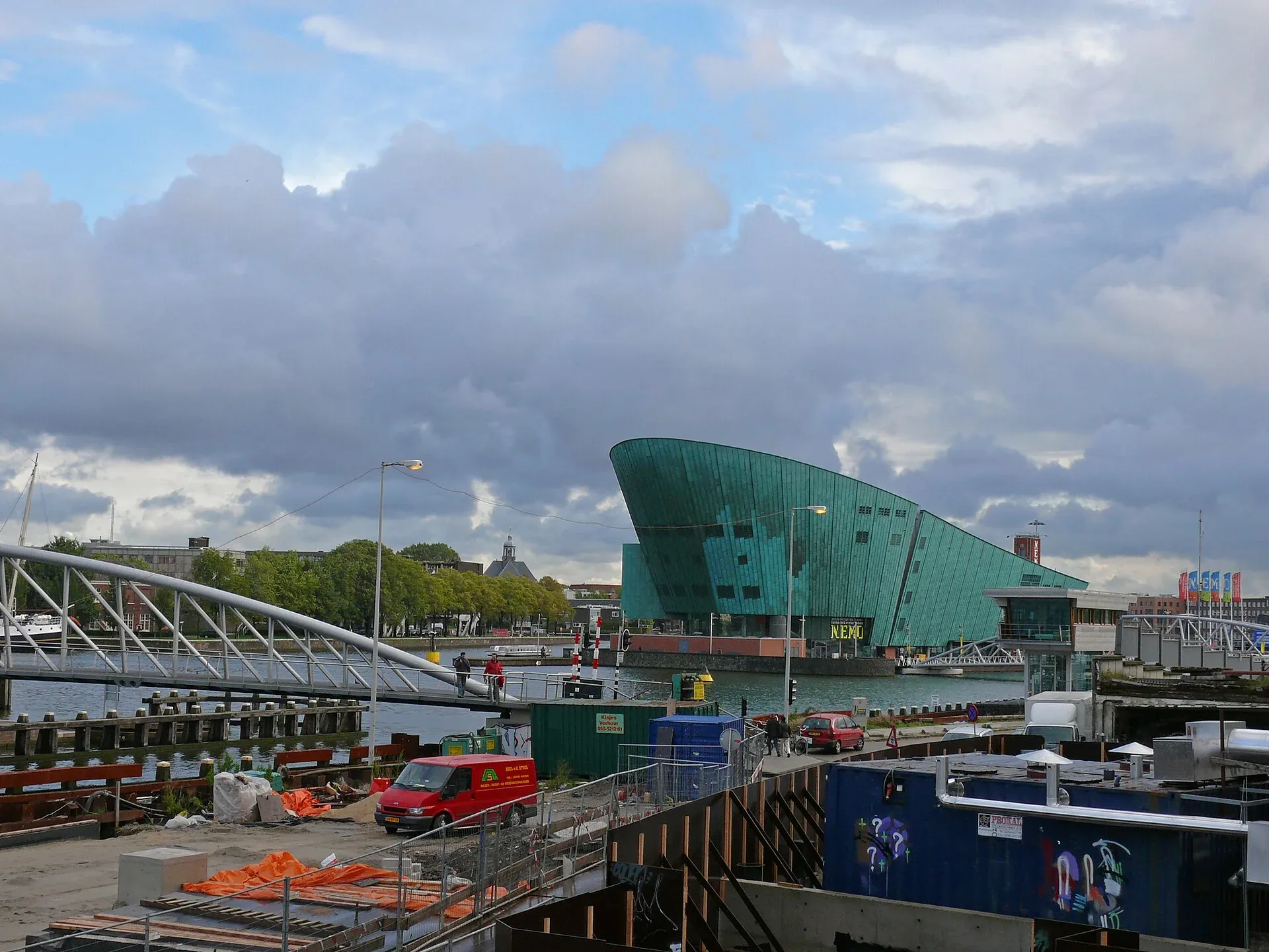 Green NEMO building beside the water under a cloudy sky.