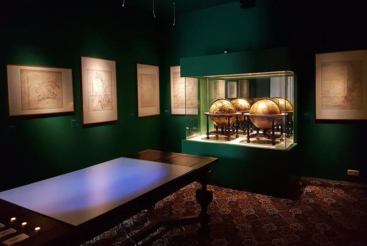 Historical gallery view with maps and globes at the Limburgs Museum.
