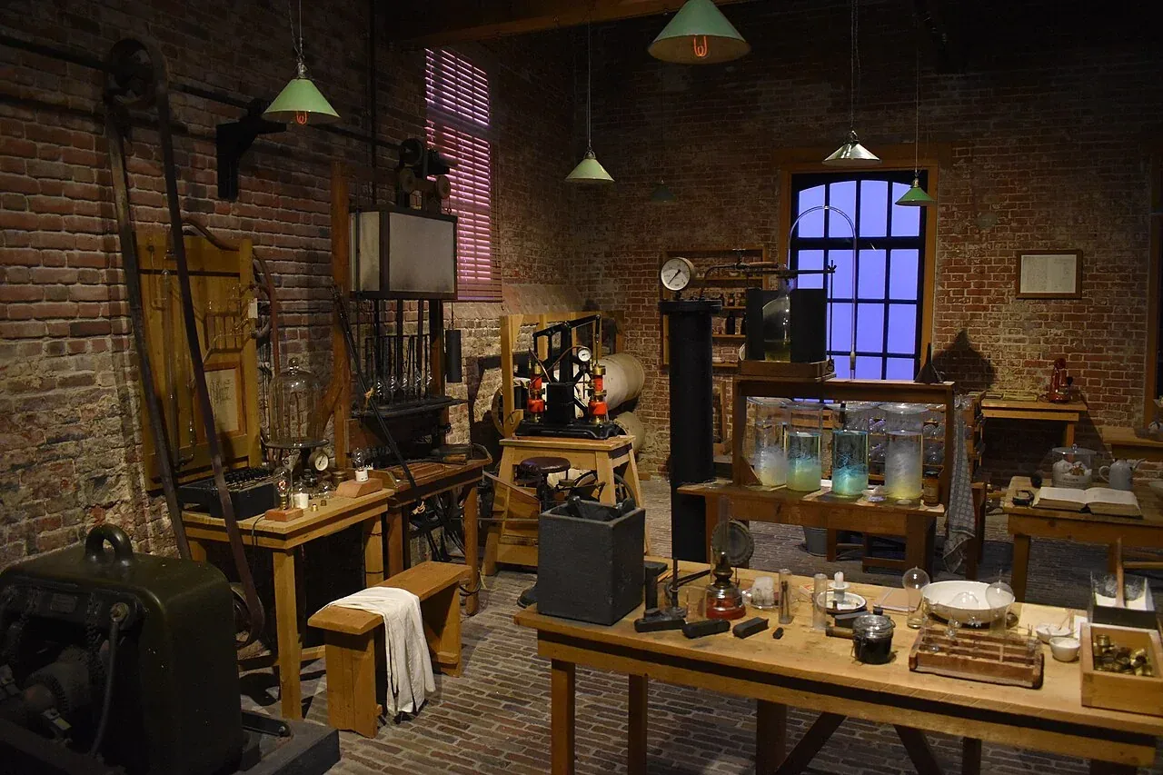 Historic workshop display with tables, equipment and glass objects.
