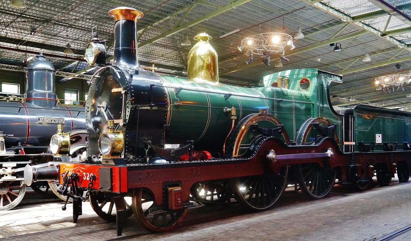 Groene historische stoomlocomotief in een overdekte museumhal.