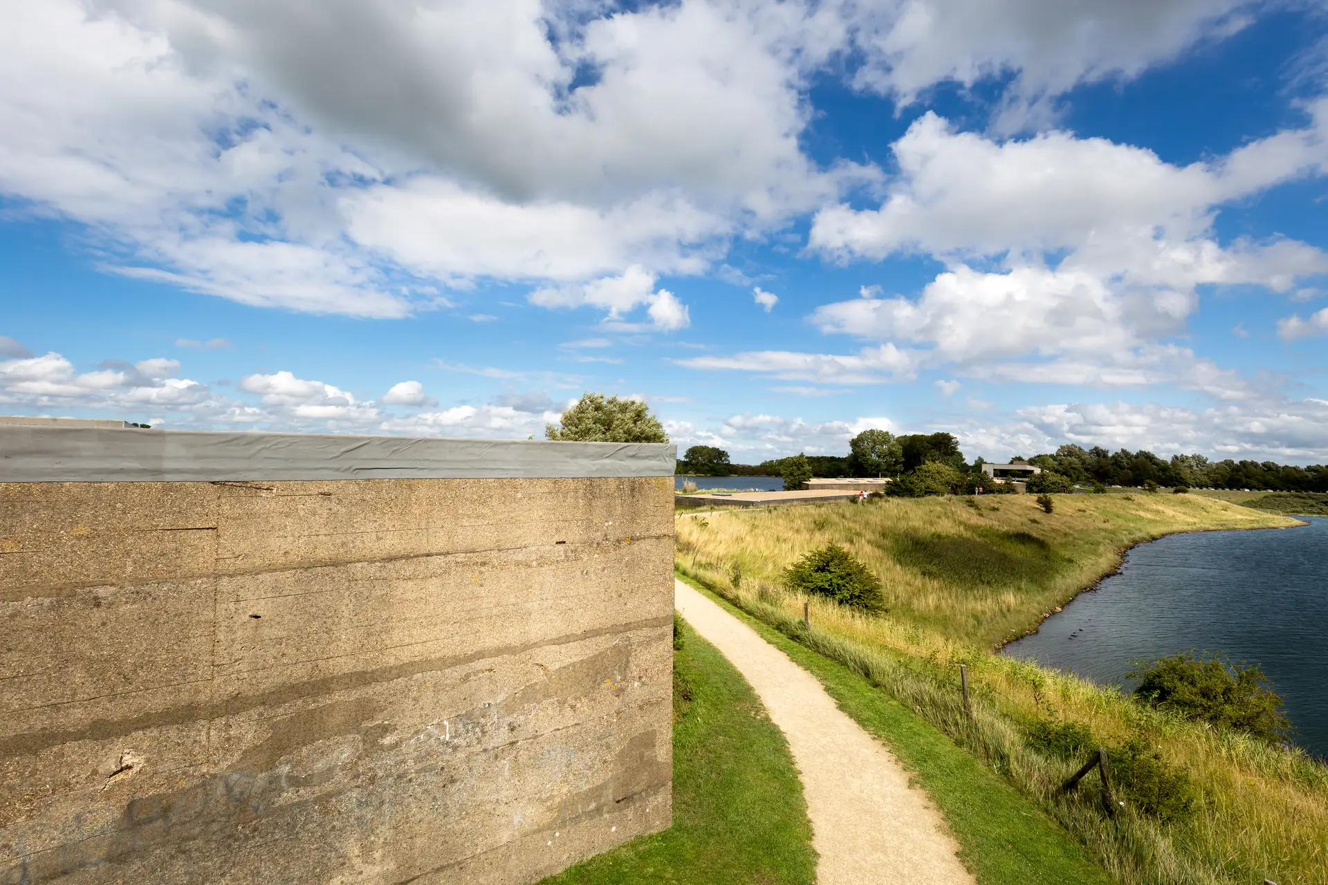 Betonnen caisson langs een pad en water bij het Watersnoodmuseum in Ouwerkerk.
