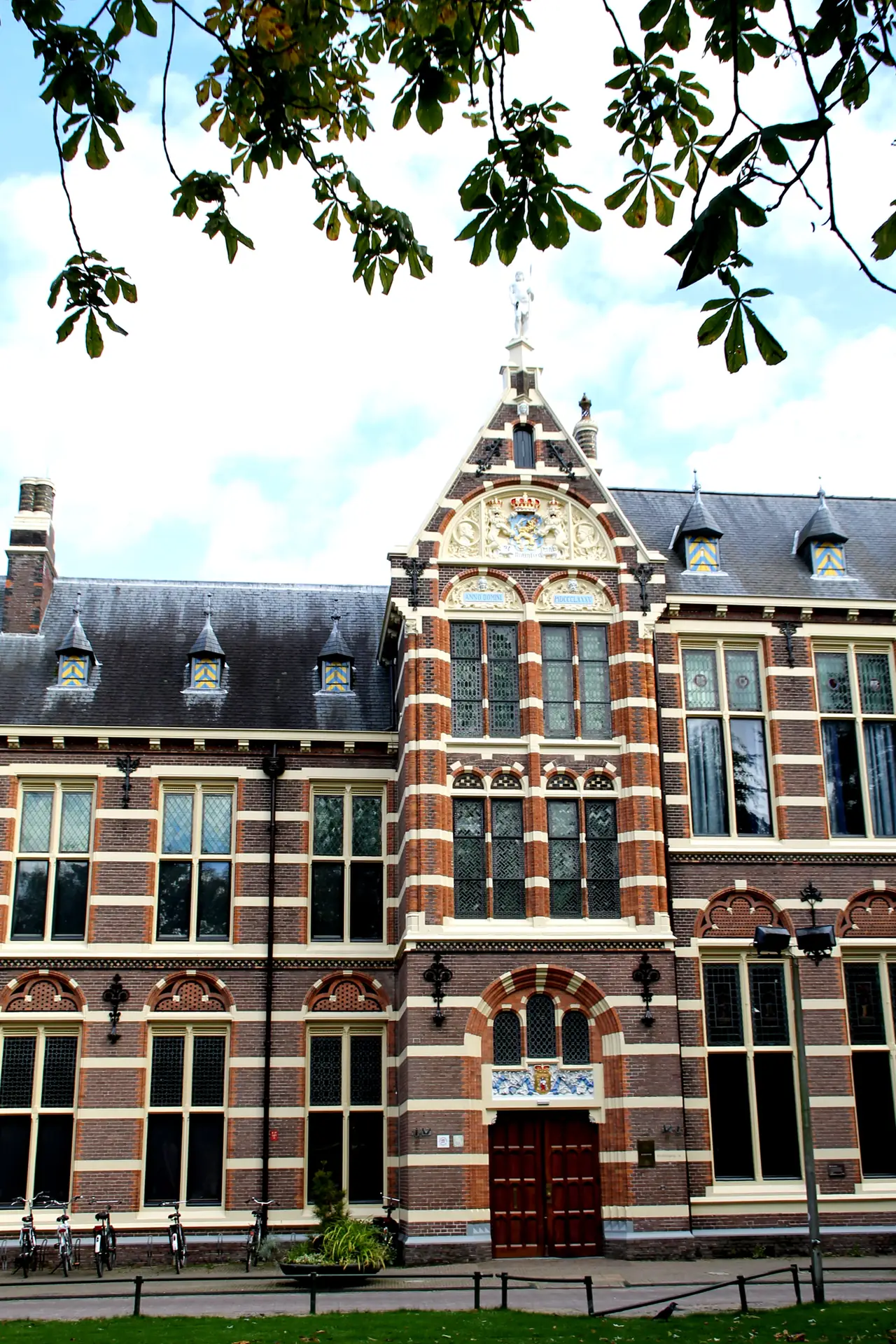 Brick façade of the historic Drents Museum beneath overhanging tree branches.